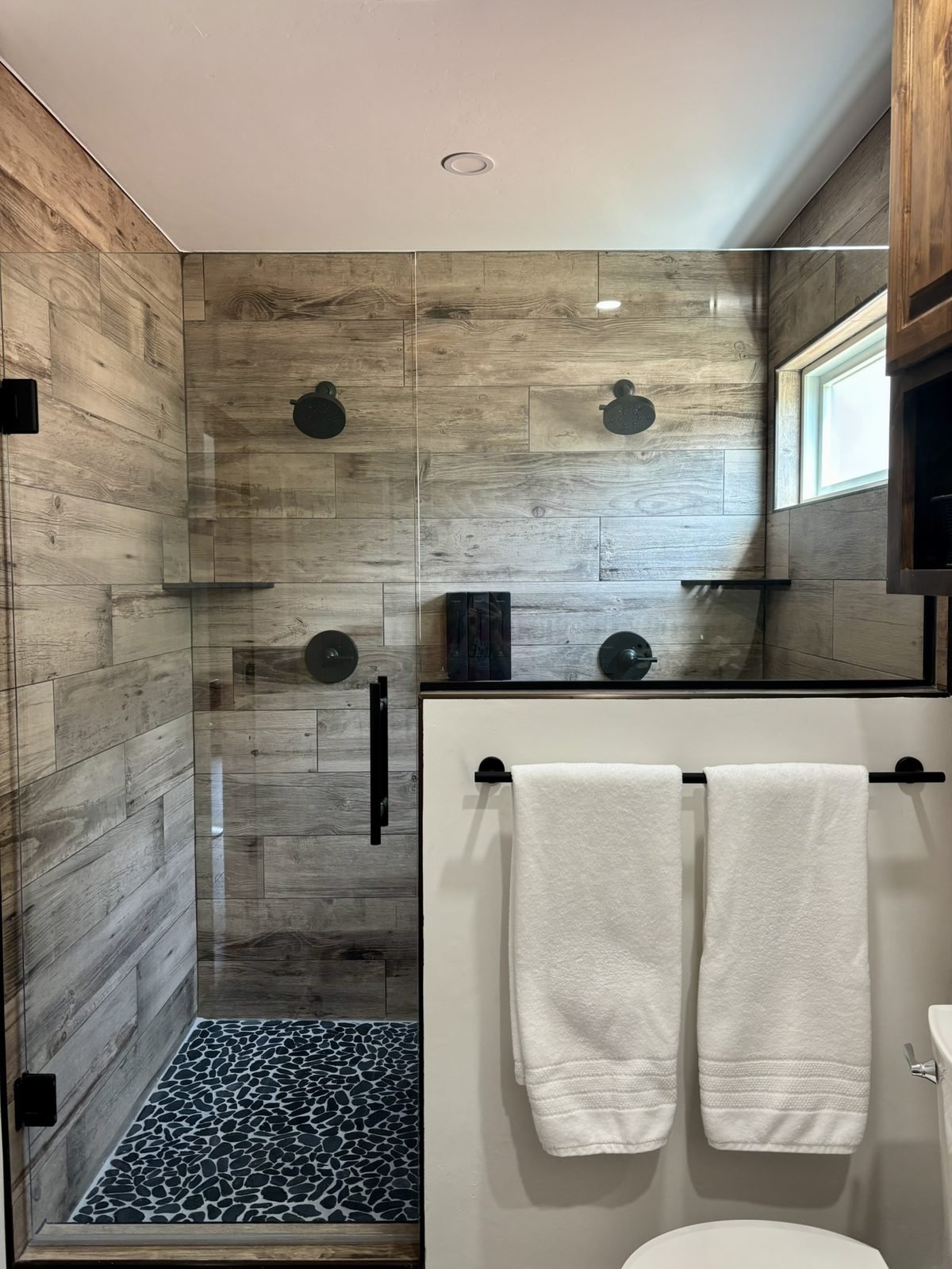 The walk-in shower with two showerheads and wood-look tile
