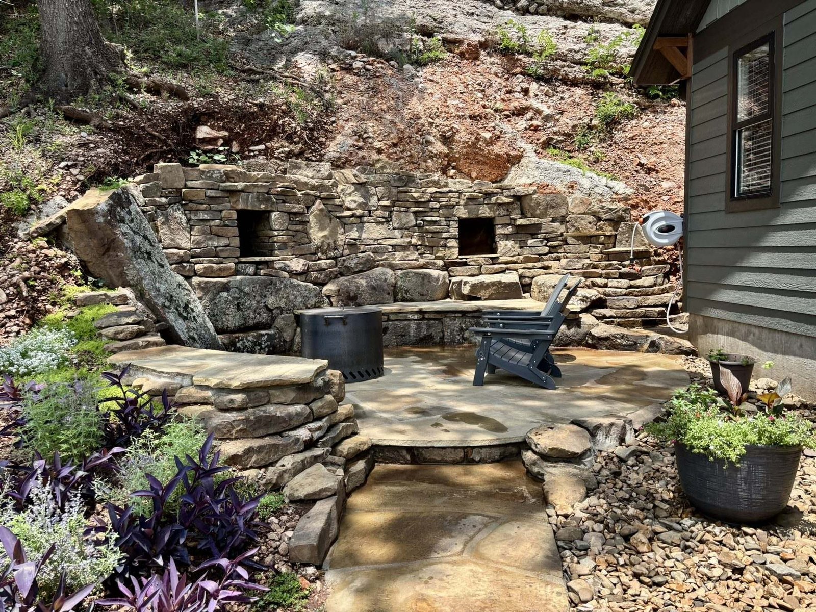 The flagstone firepit terrace with a dry-stacked stone wall and bench built into the hillside