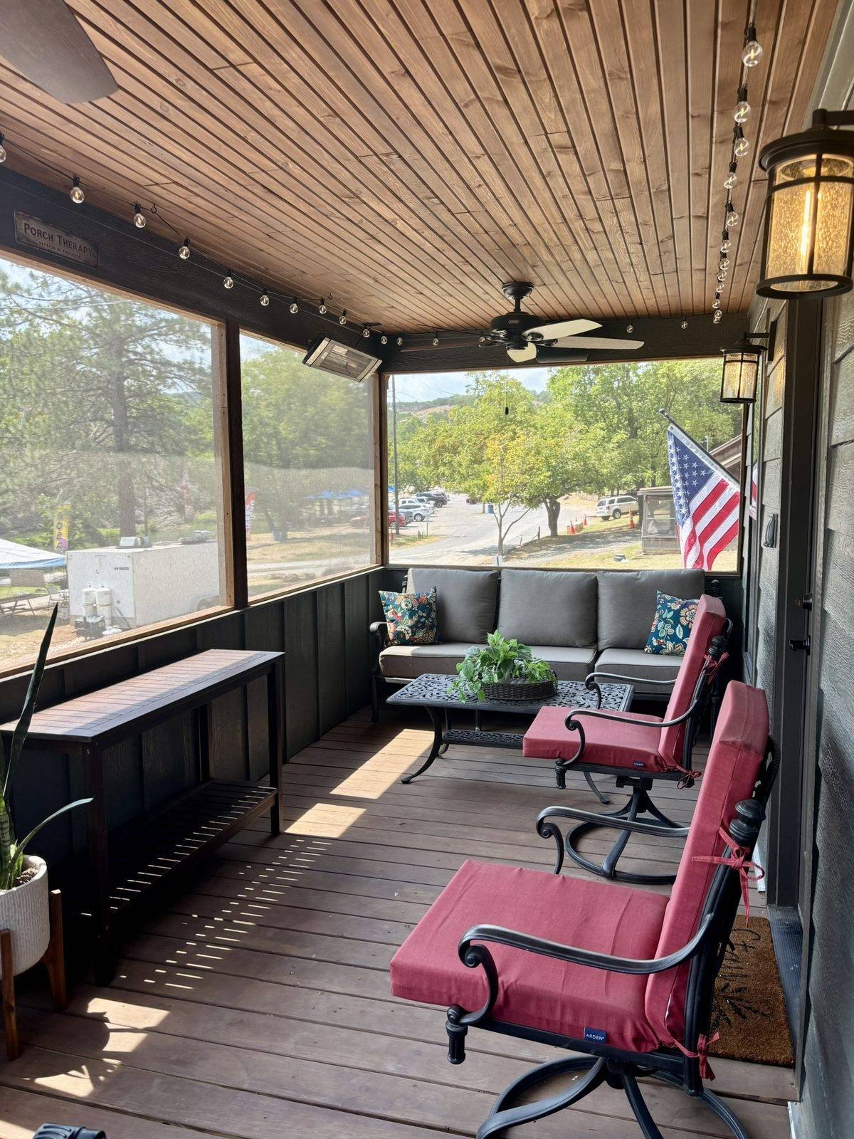 The screened porch with a table, chairs and a view out to the trees